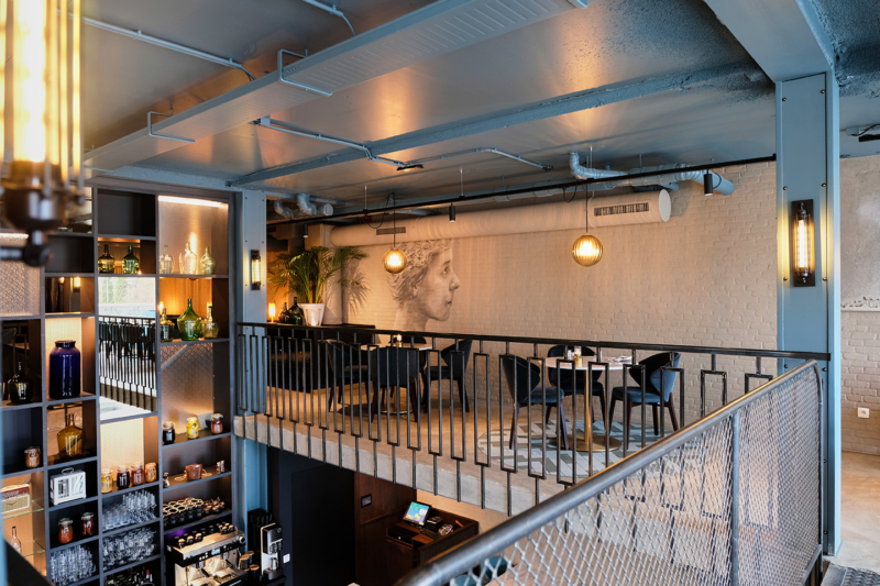 Bovenverdieping van restaurant Octave met tafels en een glazen balustrade