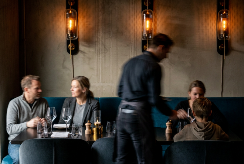 Ober aan het werk in restaurant Octave, met gasten aan tafel