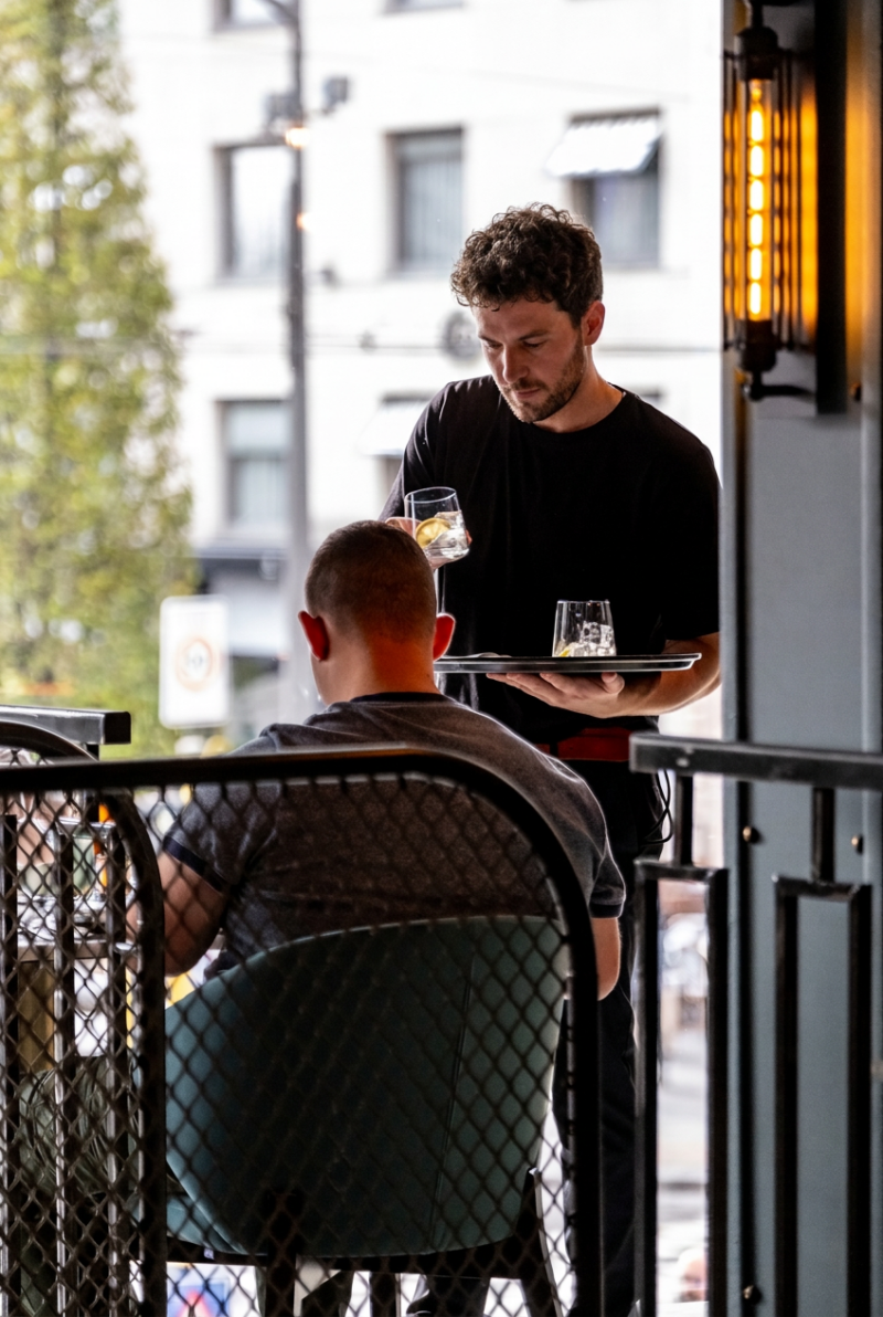 Ober brengt drankjes naar een gast op het terras van restaurant Octave in Antwerpen