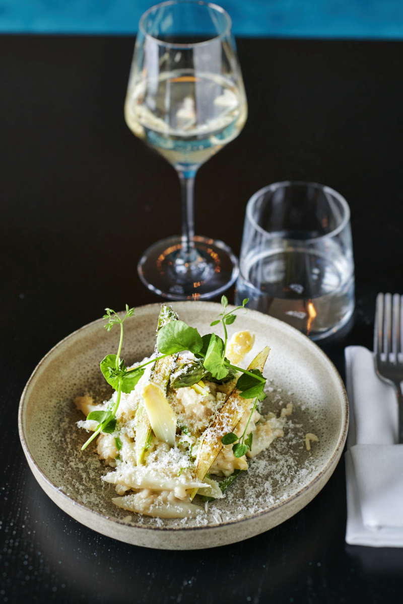 Gerecht met verse kruiden en een glas witte wijn in restaurant Octave
